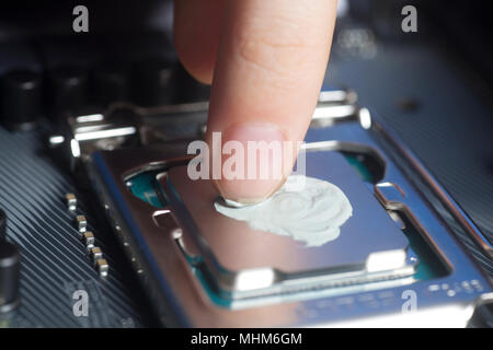 Die Wärmeleitpaste mit Finger in CPU auf dem Motherboard Nahaufnahme Stockfoto