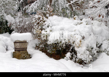 Eine Terrasse mit Gartenmöbeln, Pflanzer, Töpfe, Regenschirm und Garten Vegetation stark von einer tiefen Schnee im Winter Stockfoto