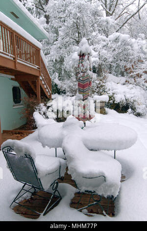 Eine Terrasse mit Gartenmöbeln, Pflanzer, Töpfe, Regenschirm und Garten Vegetation stark von einer tiefen Schnee im Winter Stockfoto