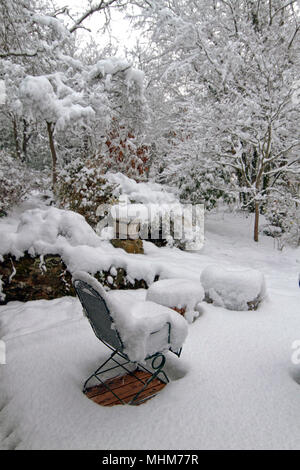 Eine Terrasse mit Gartenmöbeln, Pflanzer, Töpfe, Regenschirm und Garten Vegetation stark von einer tiefen Schnee im Winter Stockfoto