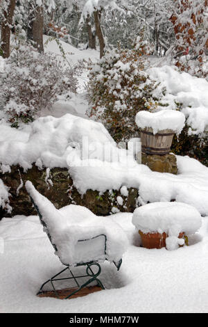 Eine Terrasse mit Gartenmöbeln, Pflanzer, Töpfe und Garten Vegetation stark von einer tiefen Schnee im Winter Stockfoto