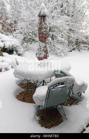 Eine Terrasse mit Gartenmöbeln, Pflanzer, Töpfe und Garten Vegetation stark von einer tiefen Schnee im Winter Stockfoto