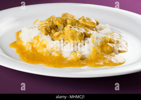 Einfaches Gericht aus Indien. Chicken Korma. Huhn auf einem mild gewürzt Coconut cremige Soße mit Reis auf weiße Platte serviert. Stockfoto