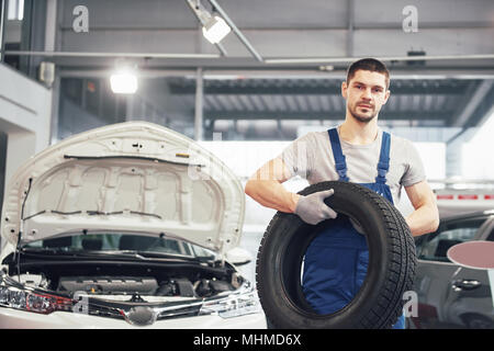 Mechaniker mit einem Reifen in der Werkstatt. Austausch des Winter- und Sommerreifen Stockfoto