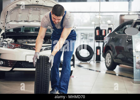 Mechaniker mit einem Reifen in der Werkstatt. Austausch des Winter- und Sommerreifen Stockfoto