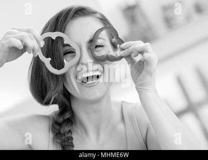 Lustige junge Frau, die Scheiben Paprika Stockfoto