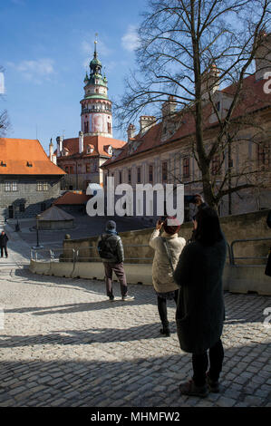 Touristen nehmen Erinnerungsfotos im Innenhof von Schloss, Cesky Krumlov, Tschechische Republik. Im Hintergrund ist der markante Turm des Schlosses. Stockfoto