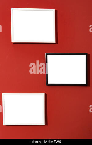 Schwarz-weiß Foto Bilderrahmen isolierten weißen, leeren Malerei Frames auf rote Wand. Mock Up. Stockfoto