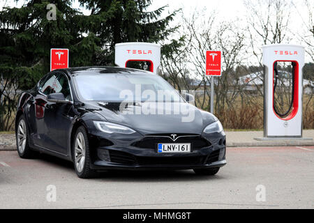 Schwarz Tesla Model S Elektroauto der aktualisiert oder Facelift Außendesign wird geladen Akku Lader Station auf einem Tag der Frühling in Paimio, Stockfoto