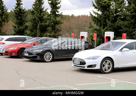 Drei Tesla Model S Elektroautos sind Laden der Batterie auf einem Kompressor Station auf einem Tag der Frühling in Paimio, Finnland - 28. April 2018. Stockfoto