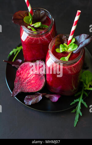 Frische rote Beete Smoothie, Zuckerrüben, Rucola und Salatblätter auf dunklem Hintergrund Stockfoto