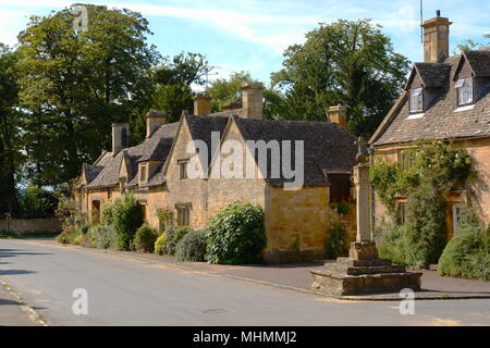 Blick auf Cottages in Stanton Village, in der Nähe des Broadway, in den Cotswolds, Gloucestershire. Im rechten Vordergrund befindet sich eine Sonnenuhr auf einem mittelalterlichen Kreuz. Stockfoto