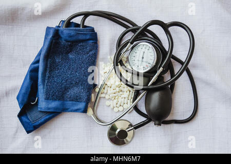 Health Care Concept - medizinische Sphygmomanometer und Pillen auf weißer Gaze Hintergrund Stockfoto