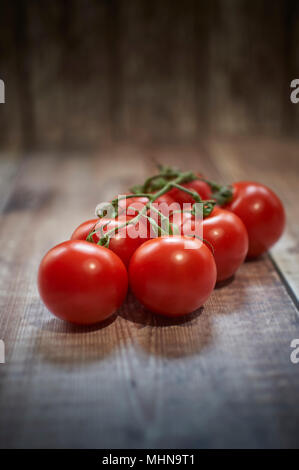 Frische Weinstock gereiften Tomaten auf einer hölzernen Tischplatte Stockfoto