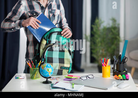 Der Student nimmt ein Notebook aus seinem Rucksack Stockfoto