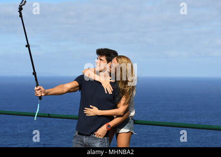 Junges Paar ein selfie auf einer Klippe mit blaues Meer, blauer Himmel im Hintergrund Stockfoto