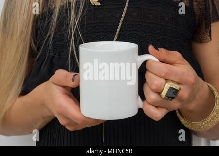 Womans Hände halten eine weiße Tasse, perfekt für die Darstellung ihres Angebots, Design auf Tassen, die Sie verkaufen. Stockfoto