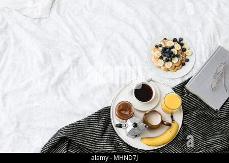 Gemütliches Frühstück Szene im Bett mit Waffeln auf einem sonnigen Wochenende Stockfoto