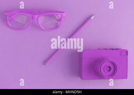 Flach von Brillen, Bleistift und retro Film Foto Kamera. Lila farbigen Hintergrund Konzept. Stockfoto