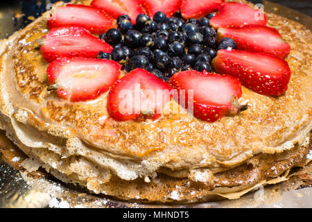 Stapel von frisch zubereiteten traditionellen leckere Pfannkuchen mit Erdbeeren, blueberrys und condenset Milch mit Honig, mit Berry und Zucker p eingerichtet Stockfoto