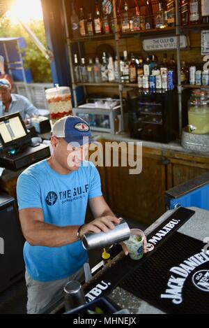 Schöner Mann gießen Schnaps trinken Cocktail an außerhalb der Waterfront Bar am Golf Restaurant, Orange Beach, Alabama. Stockfoto