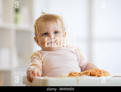 Kleines Baby essen Ihr Mittagessen und ein Chaos Stockfoto