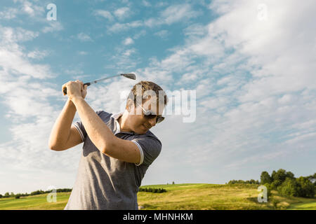 Der junge Mann das Schwingen einer Golf Club Stockfoto