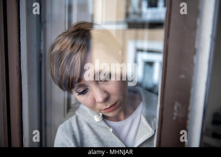 Junge schöne depressiv unglücklich kaukasische Frau besorgt und traurig durch das Fenster zu Hause. Gefühl, wertlos und Schmerzen. closeup. Depressi Stockfoto