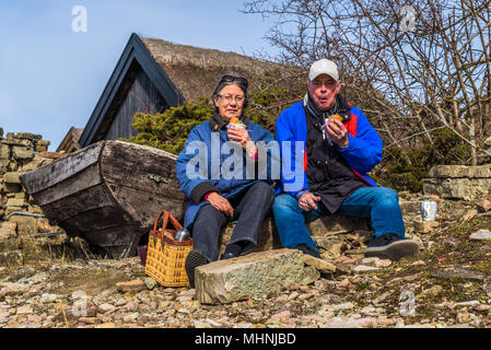 Bruddesta, Oland, Schweden - 7 April, 2018: Reisen Dokumentarfilm von Alltag und Umwelt. Senior Paar in ein Sandwich neben einem kleinen Boot. Hi Stockfoto