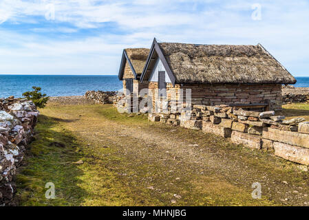 Zwei Kalkstein angeln Kabinen mit Strohdächern an der alten Bruddesta Fischerdorf auf Oland, Schweden. Horizont über Ostsee im Hintergrund. Stockfoto