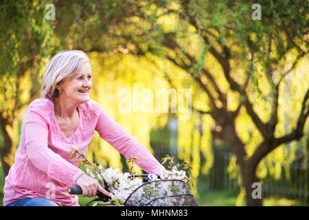 Schöne ältere Frau mit Fahrrad außerhalb im Frühjahr die Natur. Stockfoto