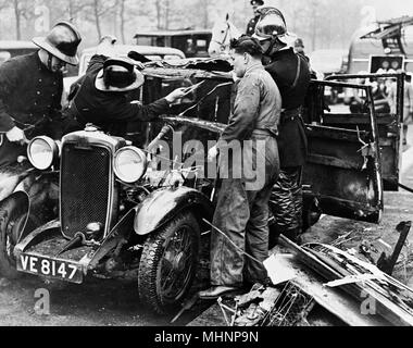 Feuerwehrleute und Mechaniker mit ausgebranntem Auto, London Stockfoto