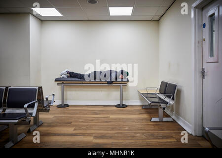 Glasgow in Schottland, Glasgow Central Mann schläft auf der Bank im Wartezimmer Stockfoto