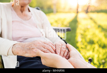 Ältere Großmutter im Rollstuhl mit Enkelin im Frühjahr die Natur. Stockfoto