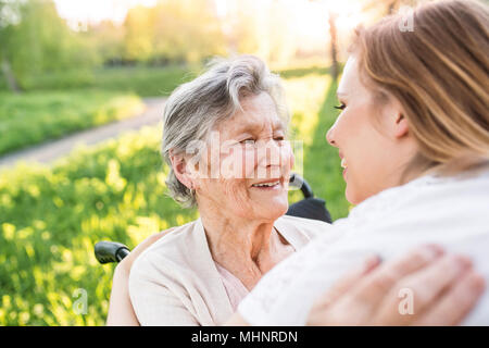 Ältere Großmutter im Rollstuhl mit Enkelin im Frühjahr die Natur. Stockfoto