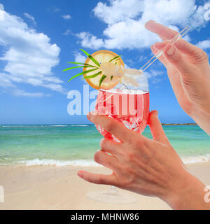 Frauen Hand mit einem bunten Cocktail an einem tropischen Strand. Stockfoto