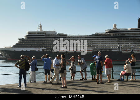 Eine Gruppe von Touristen auf der Hafenseite in Funchal, Madeira. Das kreuzfahrtschiff Queen Elizabeth ist im Hintergrund angedockt Stockfoto