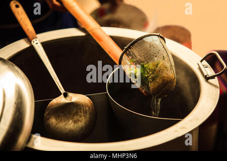 Asiatische Thai Street Food auf Ruderboot, frischen weißen Reis Nudeln Blanchiert in Nudel Siebkorb mit Griff aus Holz und warmen Aluminium lieferbar Kessel pot Stockfoto