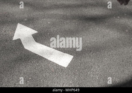 Weißer Pfeil auf Asphaltstraße Stockfoto