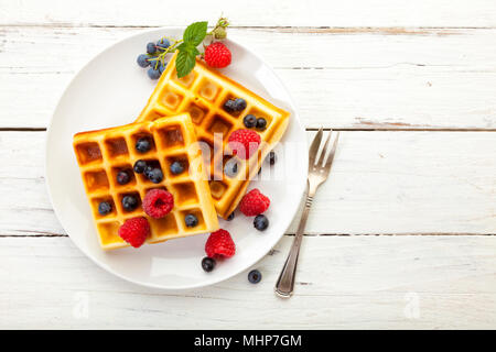 Hohe Betrachtungswinkel der Belgischen Waffeln mit Heidelbeere und Himbeere Obst auf wjite Platte, auf rustikalen Tisch, hohe Betrachtungswinkel Stockfoto