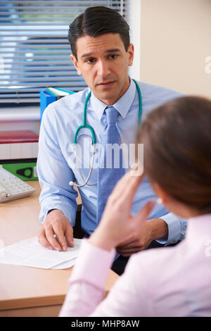 Schwere Arzt im Büro geben schlechte Nachrichten für weibliche Patienten Stockfoto