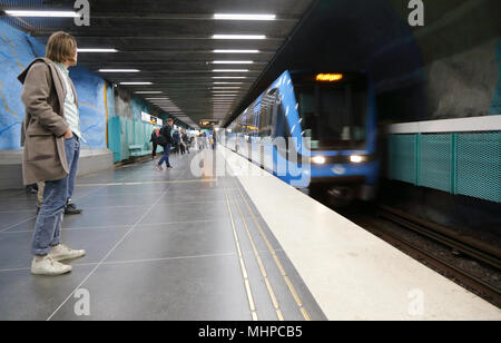 Stockholm, Schweden - 23 April 2014: Eine blaue U-Bahn Zug kommt an der Plattform an der Station Stadion in der Stockholmer U-Bahn, wo ein Mann waiti Stockfoto