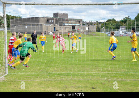 GLASGOW, Schottland - 24. AUGUST 2014: A Jugend Spieler kickt den Ball in Richtung einer offenen Ziel. Stockfoto