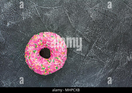 Eine einzelne Donut auf dunklem Stein Hintergrund Stockfoto