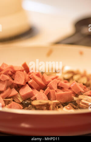 Rote und weiße Pfanne voll von Wurst, schwarze Oliven, Champignons und gehackte rote Zwiebel. Stockfoto