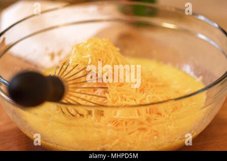 Käse und Ei Gemisch in Glasschale mit wisk. Stockfoto