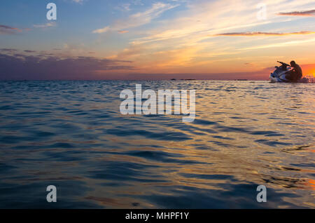 Silhouette eines Mannes auf einem Jet-ski in der Sonne auf dem Meer Sonnenuntergang im Sommer Abend Stockfoto