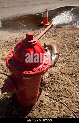 Wasser schiesst aus einem offenen Hydranten und auf die Straße, während Wasser Leitung nach der Arbeit auf dem Wasser gereinigt wird. Stockfoto