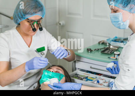 Frau beim Zahnarzt Klinik erhält der zahnmedizinischen Behandlung ein Loch in einen Zahn zu füllen. Zahnersatz und Verbundmaterial Polymerisation mit UV-Licht und Laser. Stockfoto