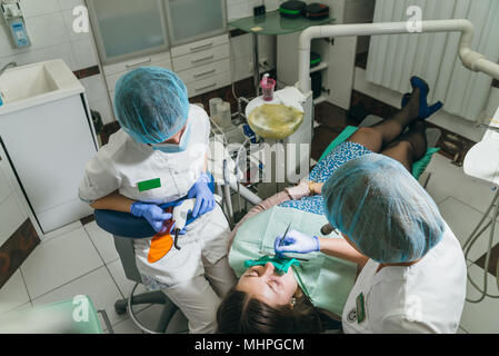Frau beim Zahnarzt Klinik erhält der zahnmedizinischen Behandlung ein Loch in einen Zahn zu füllen. Zahnersatz und Verbundmaterial Polymerisation mit UV-Licht und Laser. Stockfoto